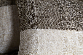 Close-up of the Munir Linen Cushion Cover by nkuku, showcasing wide charcoal and off-white stripes. Crafted from natural linen with a slubby texture, it offers a tactile, rustic look perfect for any cushion or pillow.