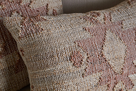 Close-up of two Nila Gul Cushion Covers by nkuku in earthy beige and rust, featuring woven geometric patterns and textured, raised stitching for a handcrafted, Indian-inspired look against a neutral background.