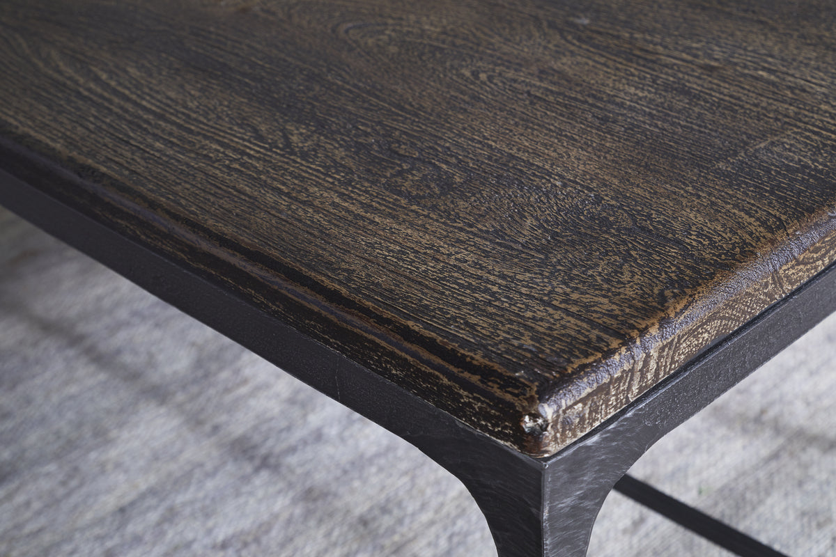Close-up of the nkuku Sita Reclaimed Wood & Iron Coffee Table in Chocolate Brown, featuring a rounded reclaimed wood top with visible grain and black metal frame, adding modern style over a light textured rug.