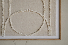 The Mauri Frayed Wall Art - Neutral by nkuku features cream-colored raised lines forming geometric shapes, including a large circle intersected by vertical lines, on a beige canvas. This neutral wall decor is wood-framed for a modern touch.