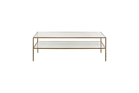 The Nakuru Iron & Glass Coffee Table by nkuku features a modern rectangular design with a slim gold metal frame, two clear glass surfaces (a top and lower shelf), and four slender legs, shown against a plain white background.