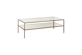 The nkuku Nakuru Iron & Glass Coffee Table features a rectangular, two-tiered design with a brass-finished iron frame and clear glass shelves, offering an elegant look ideal for modern spaces. Shown angled on a white background.