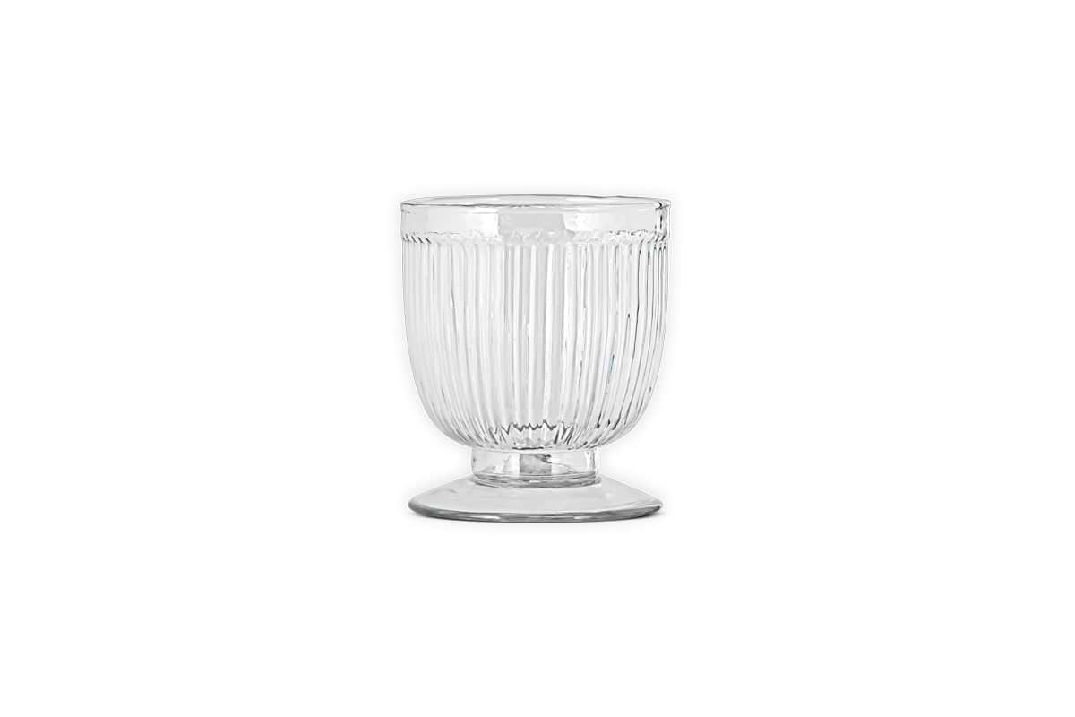 The Nia Recycled Glass Candle Holder by nkuku features a fluted, ribbed design on clear recycled glass. Set on a short stem and wide base, it catches the light beautifully, adding simple elegance to any space.