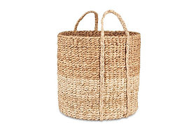 The nkuku Nkomi Basket is a tall, round hand-woven basket with two sturdy handles, featuring natural, light, and medium brown horizontal bands for a rustic look—perfect as stylish storage. Shown on a plain white background.