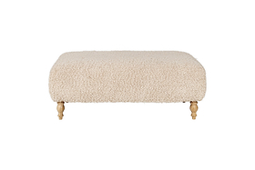 The nkuku Otas Teddy Ottoman - Off White is a rectangular boucle ottoman with rounded corners and four carved wooden legs, shown against a white background.