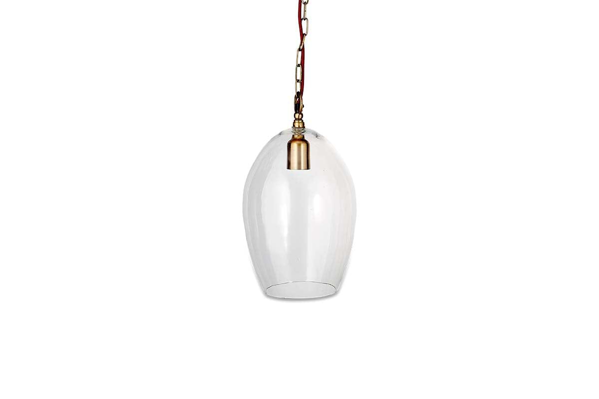 The nkuku Otoro Recycled Glass Pendant - Clear - Small Oval features an elongated clear shade, brass fittings, a brown cord, and hangs from a gold chain, creating an elegant look against a plain white background.