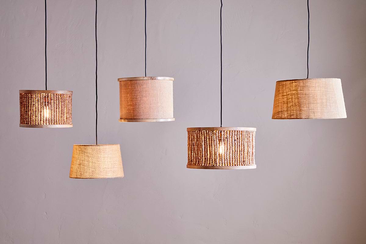 Five nkuku Dia Jute Lampshade - Natural pendant lamps hang against a plain, light wall. Each showcases unique woven or jute styles and shapes, adding warm ambient light and textured, cozy charm to modern décor.