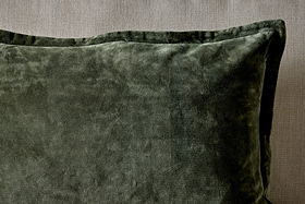 A close-up of the nkuku Pilani Velvet & Linen Cushion Cover in Moss, highlighting its deep green velvet against a textured linen backdrop.