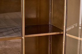 A close-up, interior shot of the nkuku Ranchi Iron Tall Cabinet, featuring glass-fronted doors and at least two shelves, highlights its elegant and timeless design.