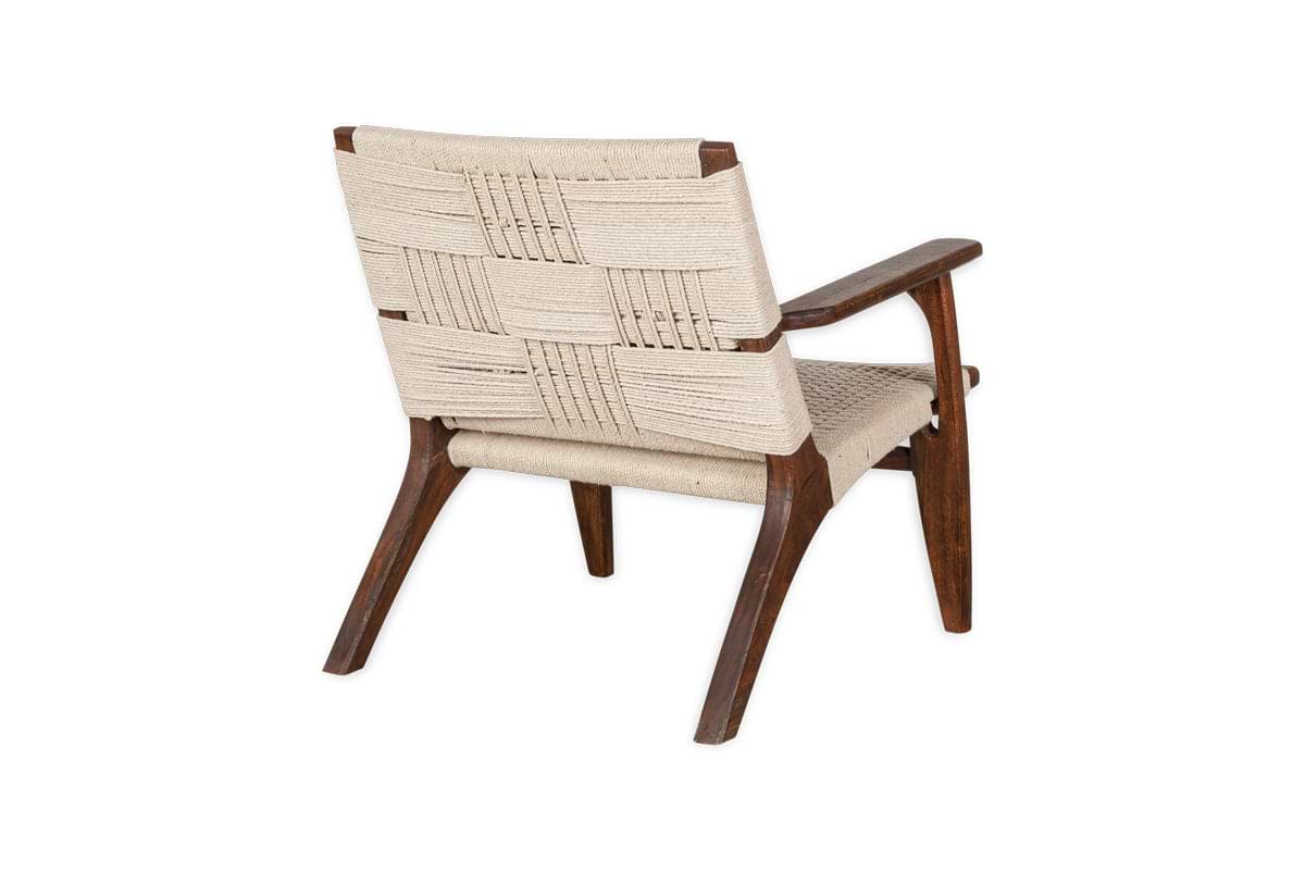 The Surat Woven Lounger - Natural by nkuku is a mid-century modern armchair with a dark acacia wood frame and hand-woven cotton rope seat and backrest, shown angled left to display its timeless design against a white background.