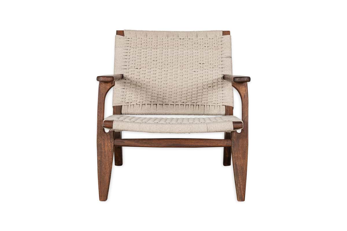 The nkuku Surat Woven Lounger - Natural features a brown acacia wood frame with a hand-woven light beige cotton rope seat and backrest, curved armrests, tapered legs, and a timeless design.