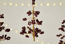 The Tanu Mango Wood Beaded Baubles - Brass & Ruby (Set of 3) by nkuku feature handmade tree ornaments crafted from gold wire and mango wood beads, hung on brown ribbons—perfect for charming festive décor.