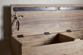 The nkuku Teni Reclaimed Wood Storage Bench with Upholstered Linen Cushion in Natural features a hinged lid, black metal strap, and twine bow. Its empty interior is divided into sections for organized storage.