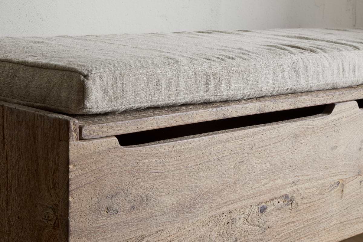 A close-up of the nkuku Teni Reclaimed Wood Storage Bench in a natural finish, featuring an upholstered linen cushion in light grey and a recessed handle for easy lid opening.