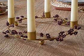The nkuku Tanu Mango Wood Beaded Candle Holder in Brass & Ruby holds four cream taper candles and features dark red berries, brass wire, and mango wood—ideal as a festive centerpiece on your table.