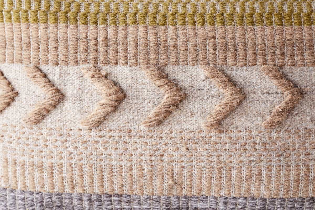The Tuleeka Wool Cushion Cover - Ochre by nkuku features a textured woven design with beige, cream, brown, ochre, and olive stripes plus raised zigzag lines—ideal for adding stylish flair to any setting.