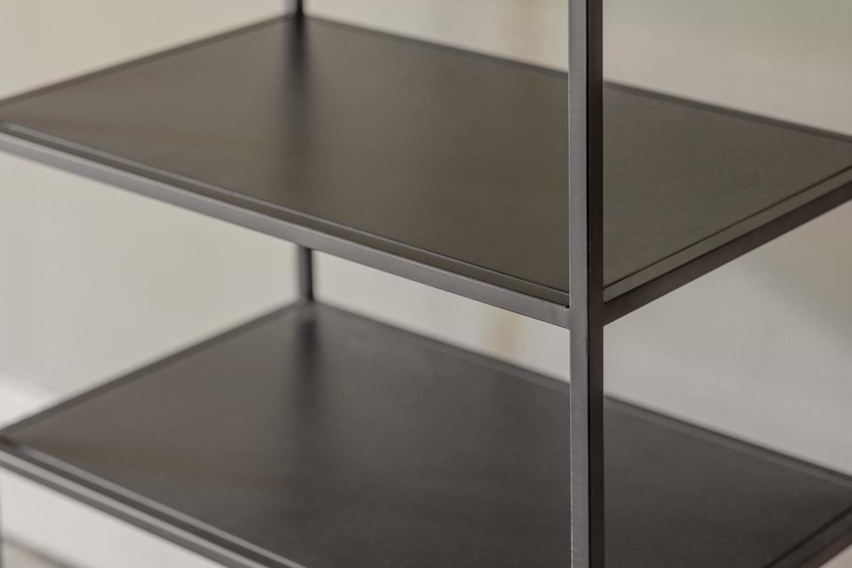 Close-up of the Tanvi Display Shelf by nkuku in black—a minimalist, narrow unit with three dark shelves and slim vertical supports against a light wall. Its matte surfaces are smooth, perfect for modern display.