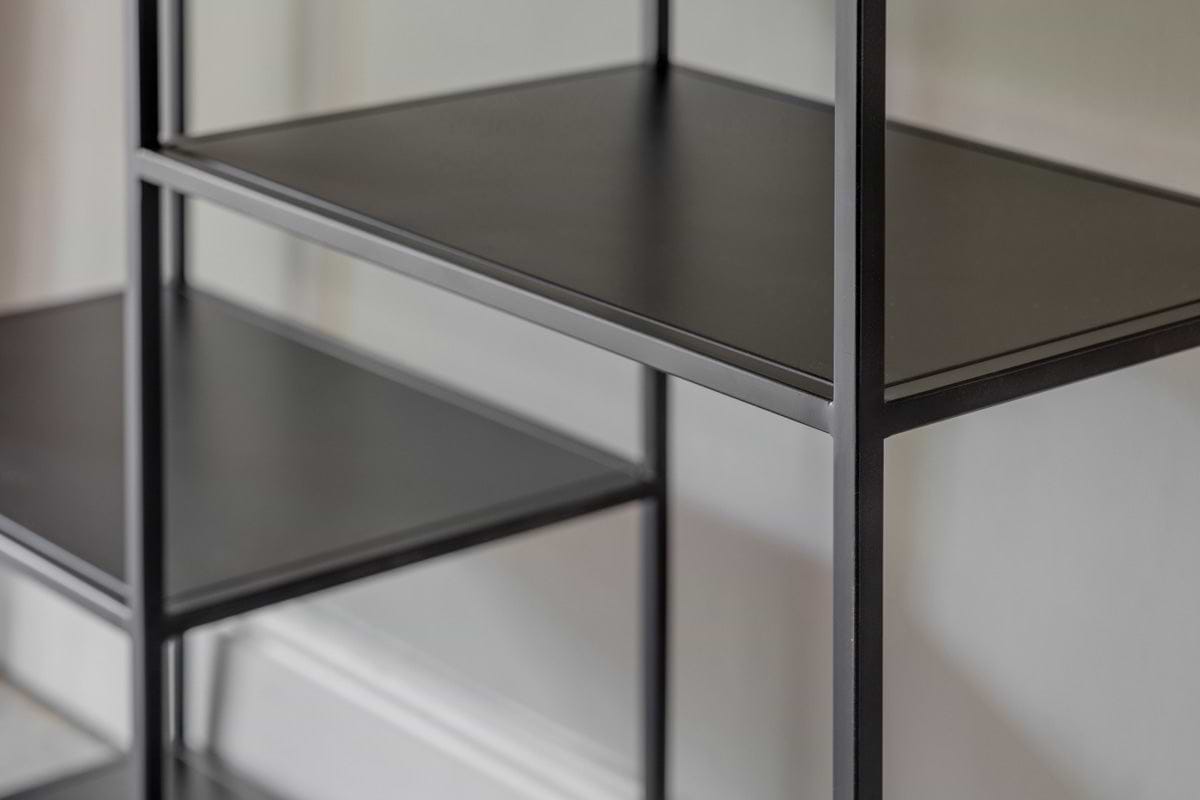 A close-up of the Tanvi Display Shelf - Black - Wide by nkuku, showcasing its modern black metal industrial design with two shelves and vertical support.