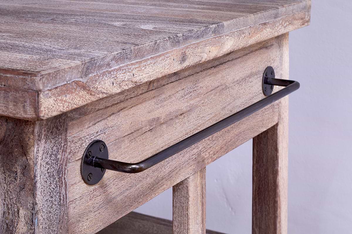 Close-up of the nkuku Tivu Reclaimed Wood Butchers Block - Natural, featuring a textured, weathered wood surface and a metal bar handle with round black brackets, set against a plain light wall.