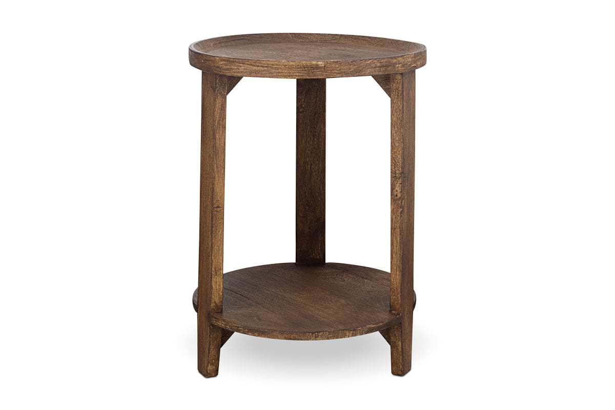 The nkuku Triveni Mango Wood Side Table features a round, solid mango wood design with a walnut stain finish, four sturdy legs, and both upper and lower circular shelves that highlight the natural wood grain.