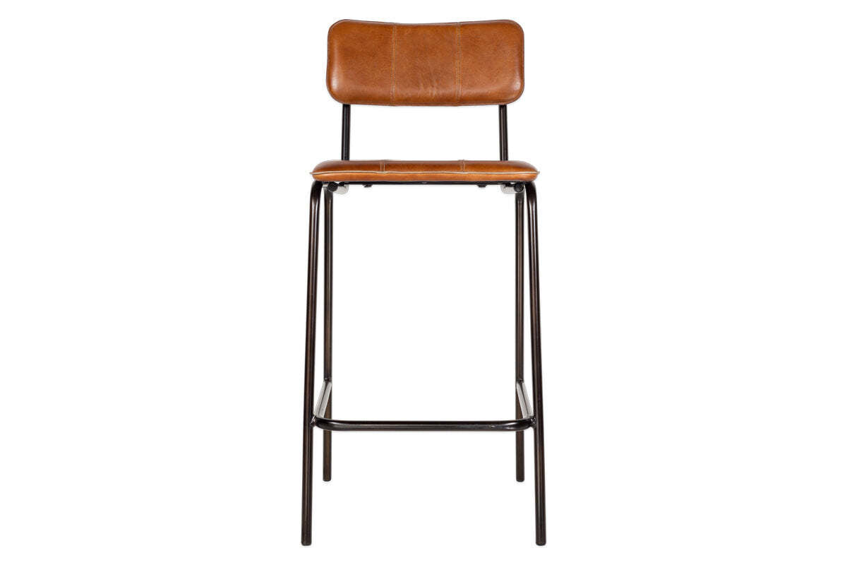 The nkuku Ukari Counter Chair in Aged Tan features tan buffalo leather upholstery with visible stitching, a padded seat and backrest, and a sleek black metal frame with four legs and footrest rail. Photographed front-on against a white background.