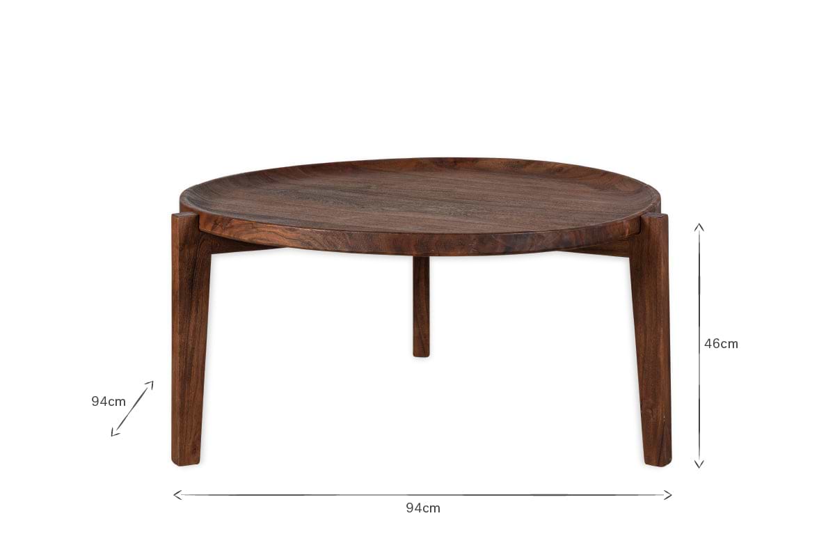 The Umar Mango Wood Coffee Table by nkuku features a sculptural round design with three legs, a curved edge, and a dark brown finish. Measuring 94cm wide by 46cm tall, it stands out beautifully against a plain white background.