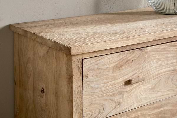 A close-up of the nkuku Vivan Grooved Chest of Drawers - Natural highlights its light wood finish, natural grain, and texture. This minimalist bedroom piece features a rectangular drawer with a small wooden handle.