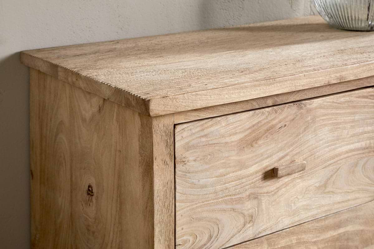 A close-up of the nkuku Vivan Grooved Chest of Drawers - Natural highlights its light wood finish, natural grain, and texture. This minimalist bedroom piece features a rectangular drawer with a small wooden handle.