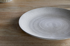 The nkuku Valinha Earthenware Dinner Plate in grey features a large, round design with a subtle concentric pattern and smooth matte finish, making it an elegant addition to your tableware collection.