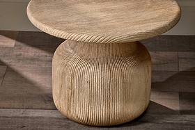 The Vivan Grooved Wood Side Table by nkuku is crafted from sustainable mango wood, featuring a round, ribbed design with a thick base that narrows elegantly to support its wide top—perfect for contemporary spaces.