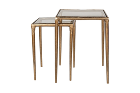 The nkuku Gilasi Cast Metal & Glass Nesting Side Tables (Set of 2) feature antique brass frames, slender legs, and square glass tops. The smaller table fits partially under the larger one for versatile use. Shown together against a white background.
