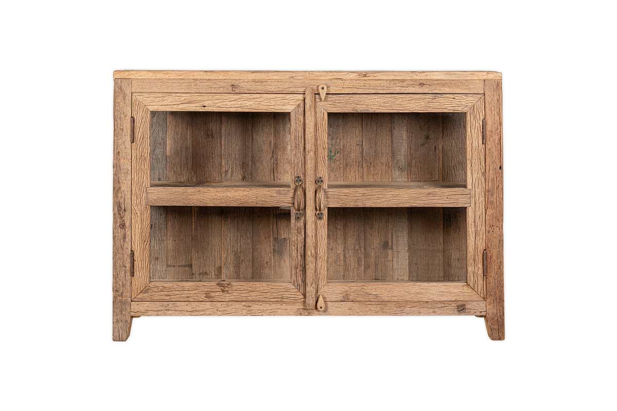 The nkuku Ibo Reclaimed Wood & Glass Sideboard - Natural features a rectangular, rustic design with two glass-paneled doors, antique brass handles, short legs, and a natural wood finish.