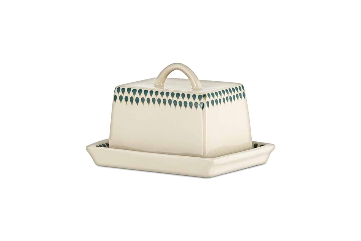 The nkuku Juniper Drop Butter Dish - Cream & Juniper features a rectangular ceramic design with a cream lid edged in green drops and a curved handle, offering both charm and elegance to your table.