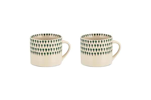 The nkuku Juniper Drop Mug - Cream & Juniper - Small (Set of 2) features two cream ceramic mugs with unique handles and juniper green drop details, displayed side by side on a white background.