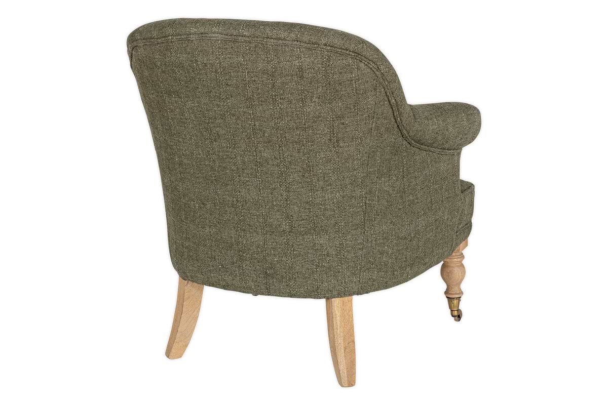 The Kiana Cotton Armchair - Moss by nkuku is shown from the back. It features green cotton upholstery, a curved backrest, tub shape, hand-carved light mango wood legs, and a small metal caster on one front leg against a white background.