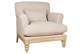 The Kashi Linen Armchair - Natural by nkuku features beige upholstery in natural linen, rounded arms, a plush seat cushion, matching lumbar pillow, and exposed light mango wood legs with decorative carvings.