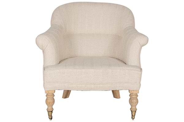 The Kiana Cotton Armchair - Natural by nkuku features beige cotton upholstery, curved armrests, a rounded backrest, and hand-carved mango wood legs with turned brass-caster front legs.