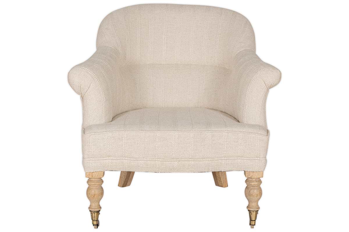 The Kiana Cotton Armchair - Natural by nkuku features beige cotton upholstery, curved armrests, a rounded backrest, and hand-carved mango wood legs with turned brass-caster front legs.