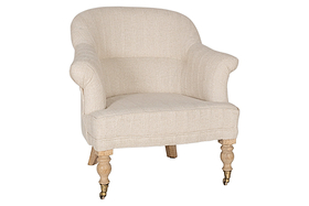 The Kiana Cotton Armchair - Natural by nkuku features beige cotton upholstery, a curved backrest, rounded arms, and hand-carved mango wood legs—two with brass caster wheels.