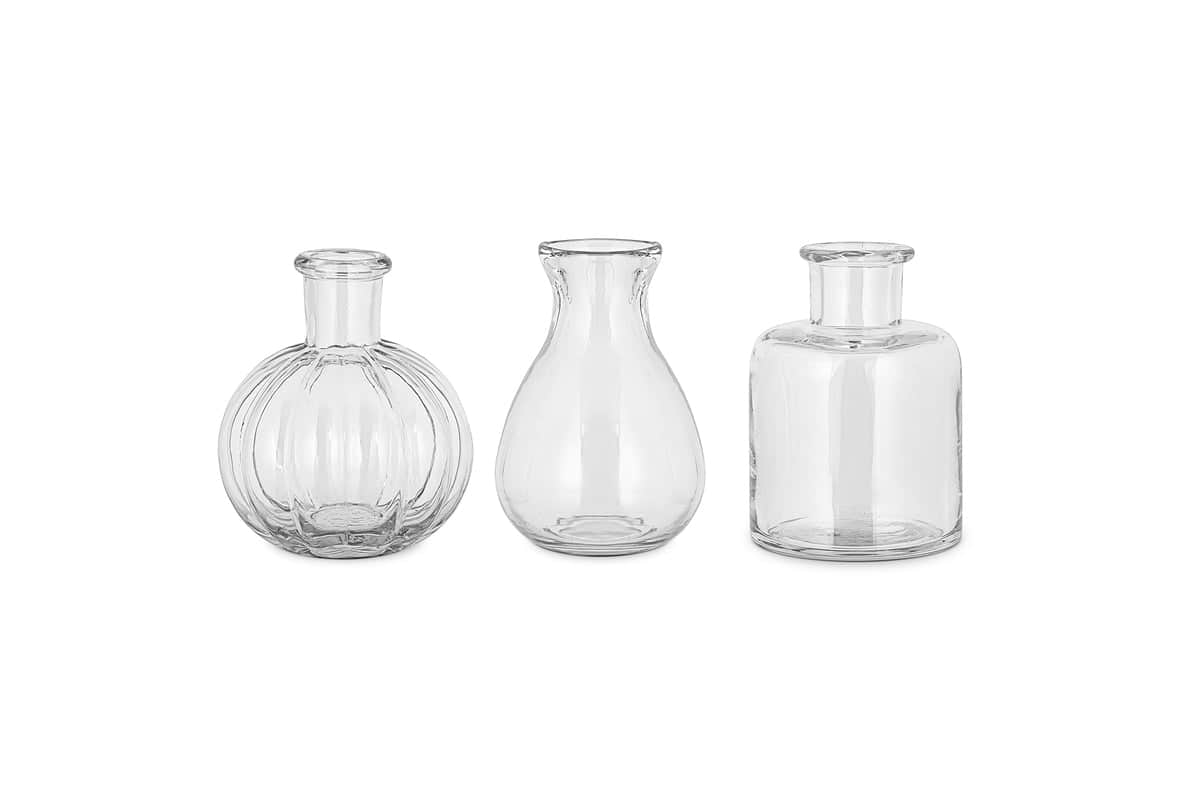 The nkuku Mayumi Recycled Glass Bud Vases - Clear (Set of 3) features three uniquely shaped clear vases, perfect for showcasing your favorite stems as elegant bud vases.