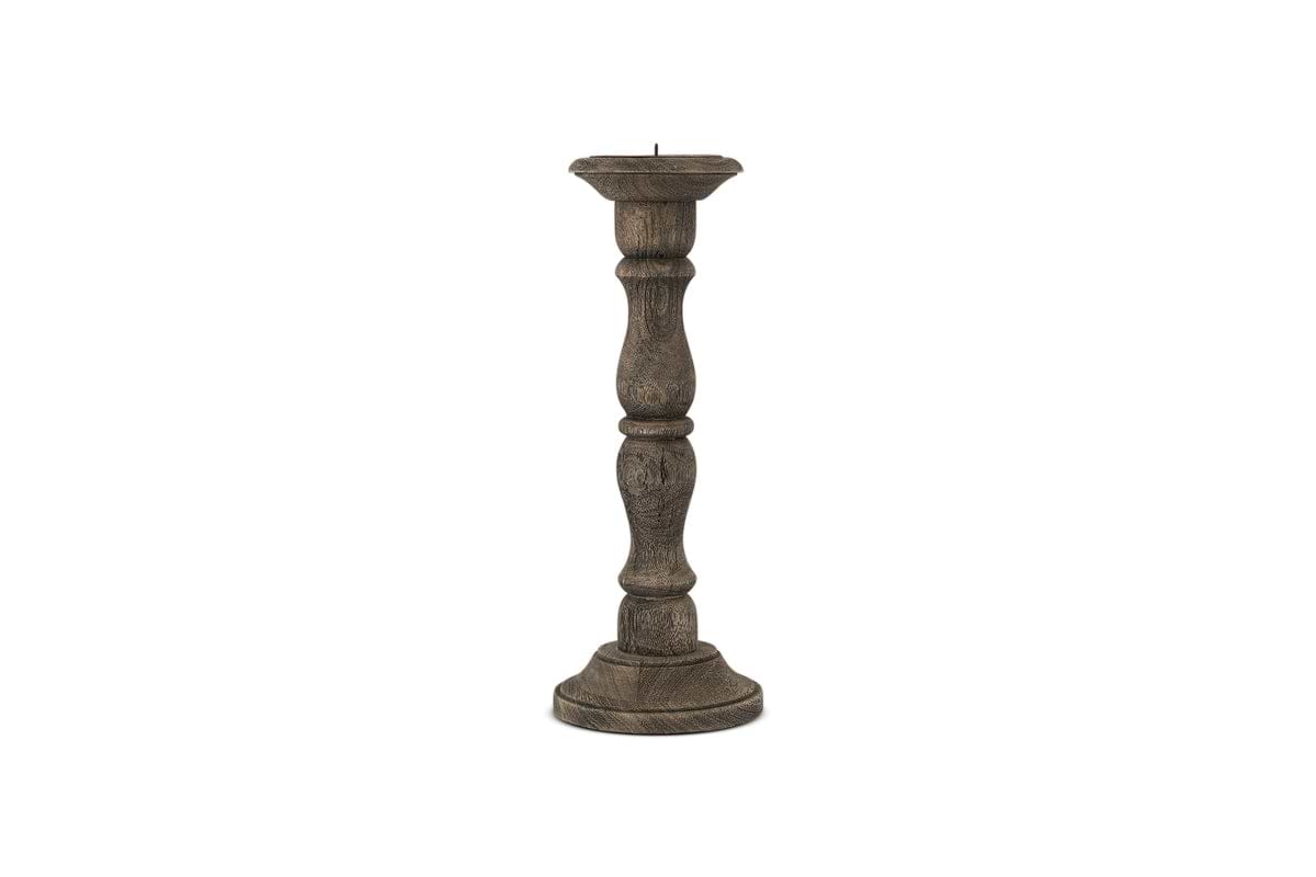 The Nayati Rustic Wood Pillar Candle Stick by nkuku features a tall, dark-stained sustainable mango wood design with a rounded base and ornate column. It has a flat top with metal spike, perfect for rustic decor. Shown on a plain white background.