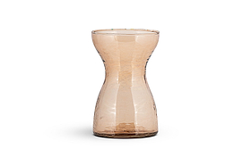 The nkuku Enir Hyacinth Vase in Dusty Terracotta features a tall, narrow, hourglass design with lightly hammered glass for a hand-blown look. Displayed on a white background, it casts a subtle shadow beneath it.