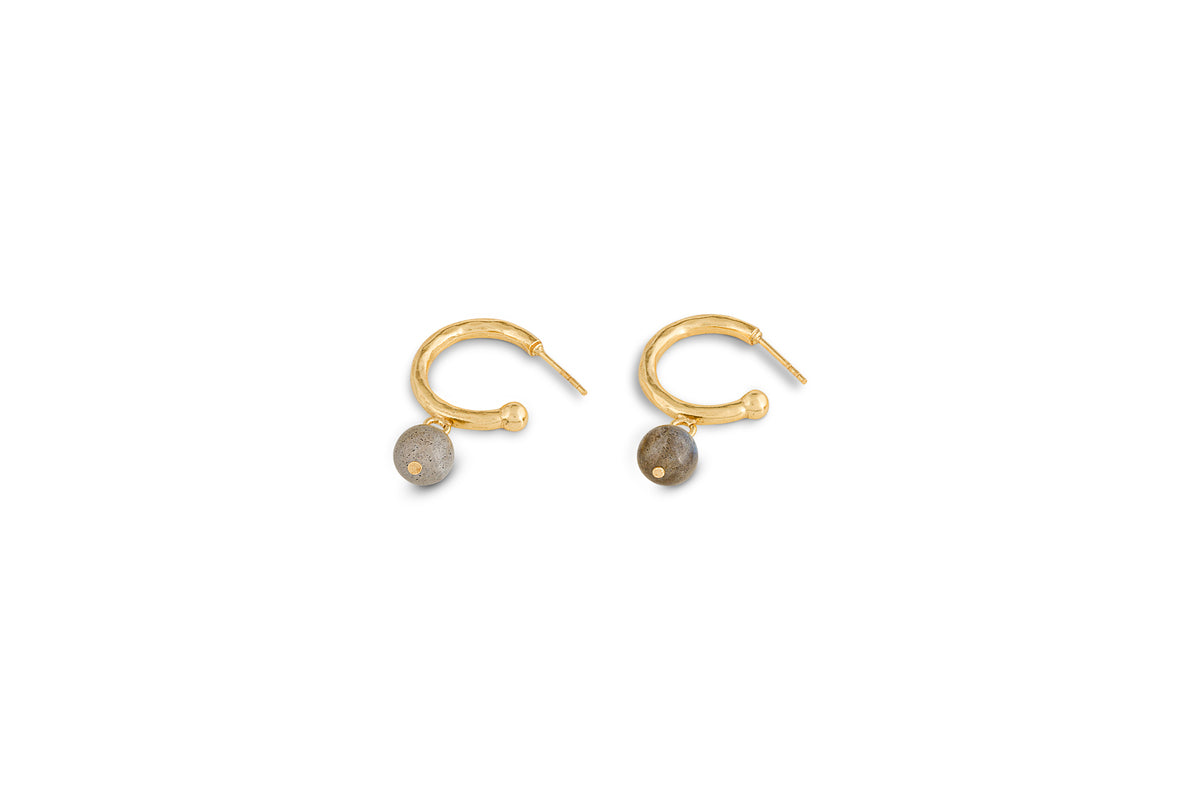 The Marai Labradorite Earrings by nkuku feature a single round gray labradorite bead in a gold drop design, displayed on a white background with upward posts—an elegant jewellery gift.