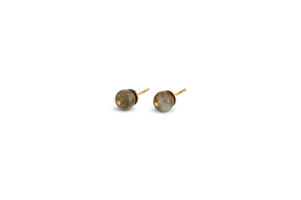 The Marai Labradorite Stud Earrings by nkuku feature round, gray labradorite stones set in sleek gold bezels with straight post backings—an elegant minimalist choice for jewelry lovers.