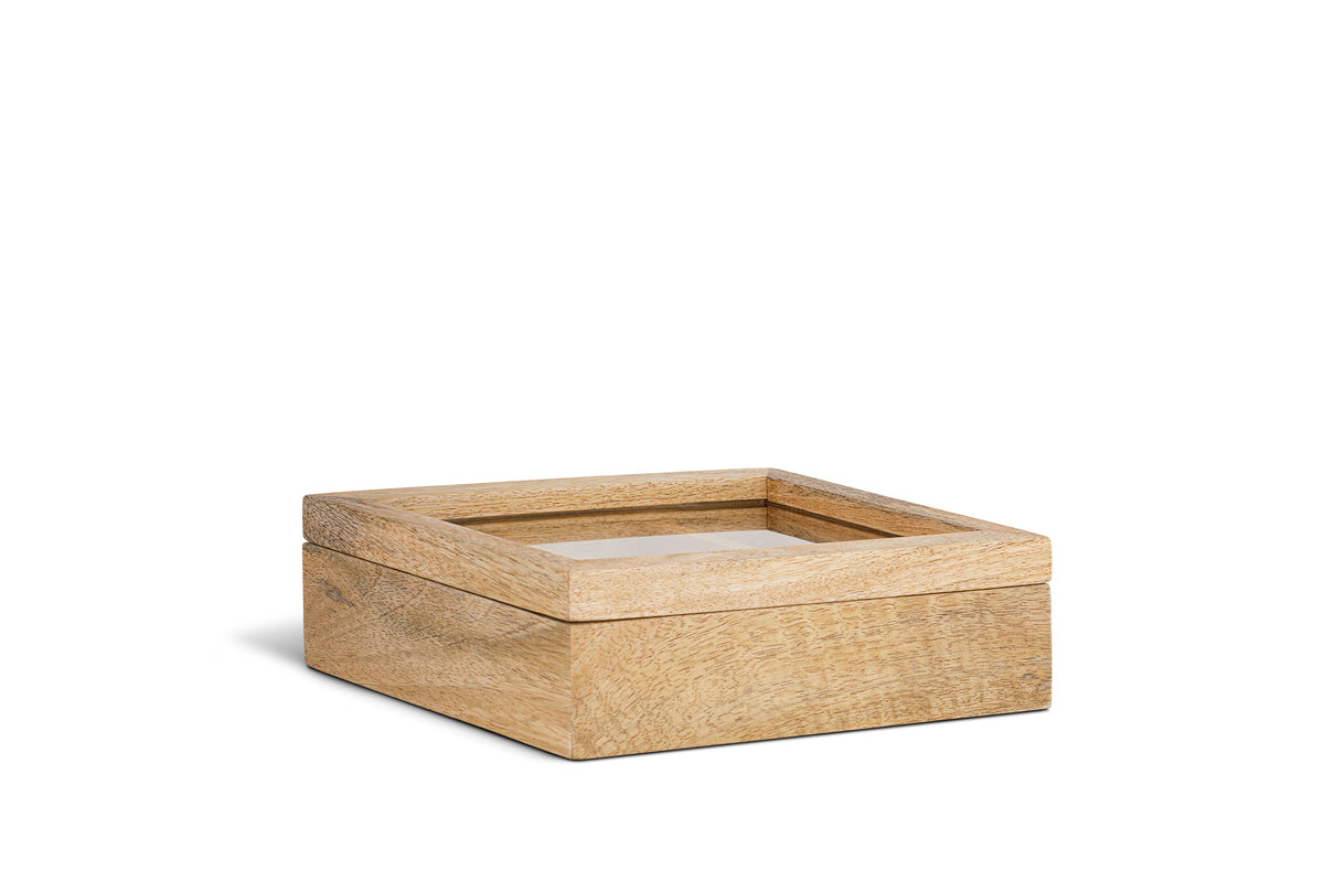 The Kabani Mango Wood Jewellery Box by nkuku features a square design in natural mango wood with smooth grain, clean edges, and a clear glass top. The lid is raised to show it’s separate from the base, all set against a white background.