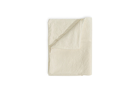 The Cela Hemp & Cotton Duvet Cover - Natural by nkuku is neatly folded against a white background, with one corner turned up to showcase its soft, lightweight blend and subtle texture—ideal for sustainable bedding.