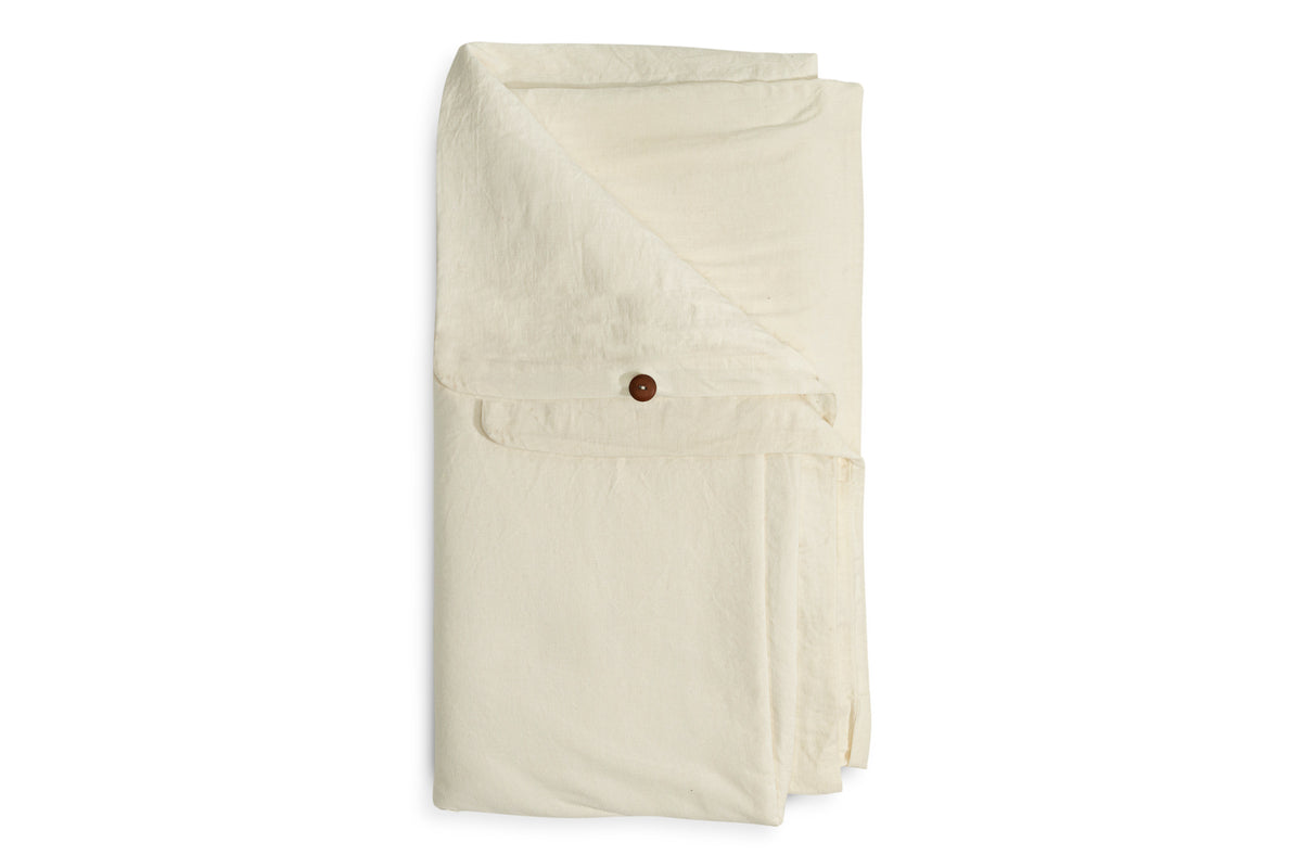 The Cela Hemp & Cotton Duvet Cover - Natural by nkuku, in off-white with a brown button flap, is neatly displayed on a white background, highlighting its soft, linen-like texture and minimalist design with smooth edges.