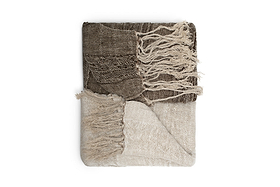 The nkuku Munir Linen Throw - Charcoal features a folded, two-tone design with slubby texture. The top is dark charcoal with matching fringed tassels, while the bottom is lighter beige. Displayed neatly on a white background.