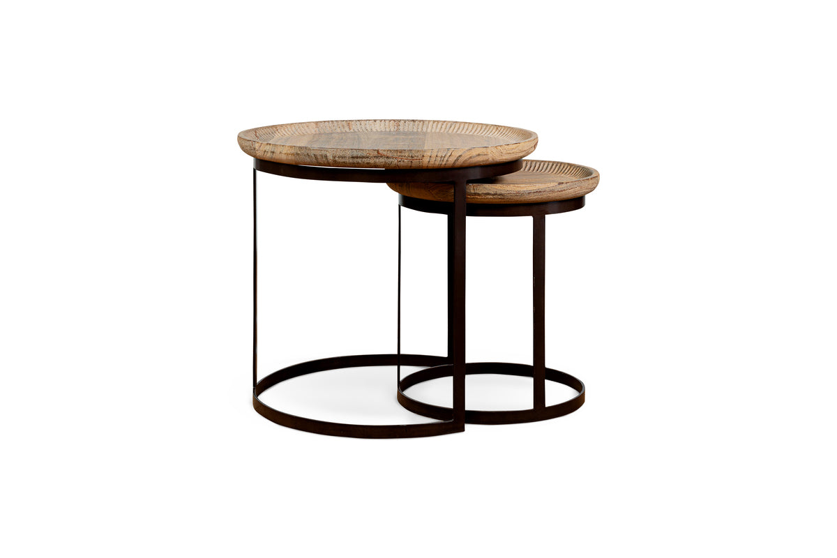 The Nisha Carved Reclaimed Wood & Iron Nesting Side Tables by nkuku feature natural, grain-patterned tops and slim black iron frames. The smaller table partially nests beneath the larger, highlighting a modern minimalist design.