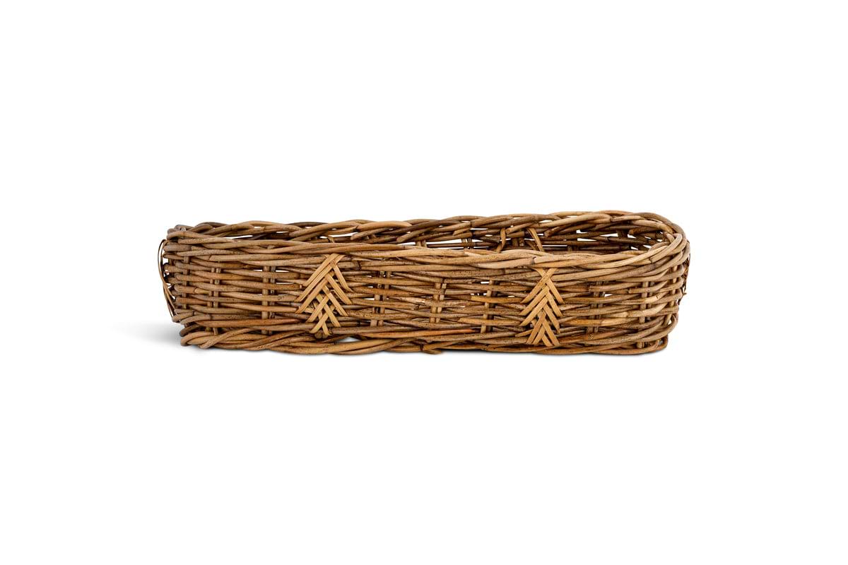 The Bersama Rattan Bread Basket by nkuku is a rectangular, shallow handwoven rattan basket with chevron accents and braided edges—ideal as tabletop decor on a plain white background.